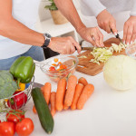 A food preparation area with a man and a woman working together to cut vegatables