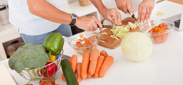 A food preparation area with a man and a woman working together to cut vegatables