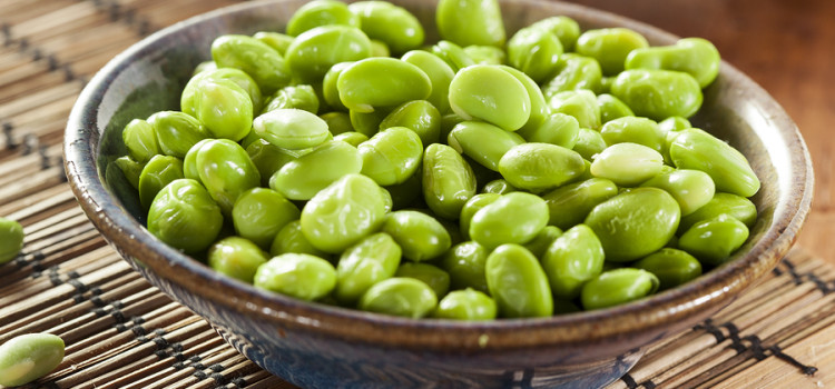 Edamame Beans in a brown ceramic bowl, placed upon a bamboo placemat