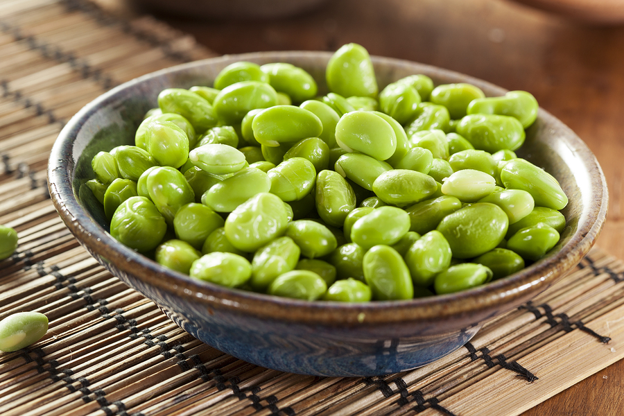 Edamame Beans in a brown ceramic bowl, placed upon a bamboo placemat