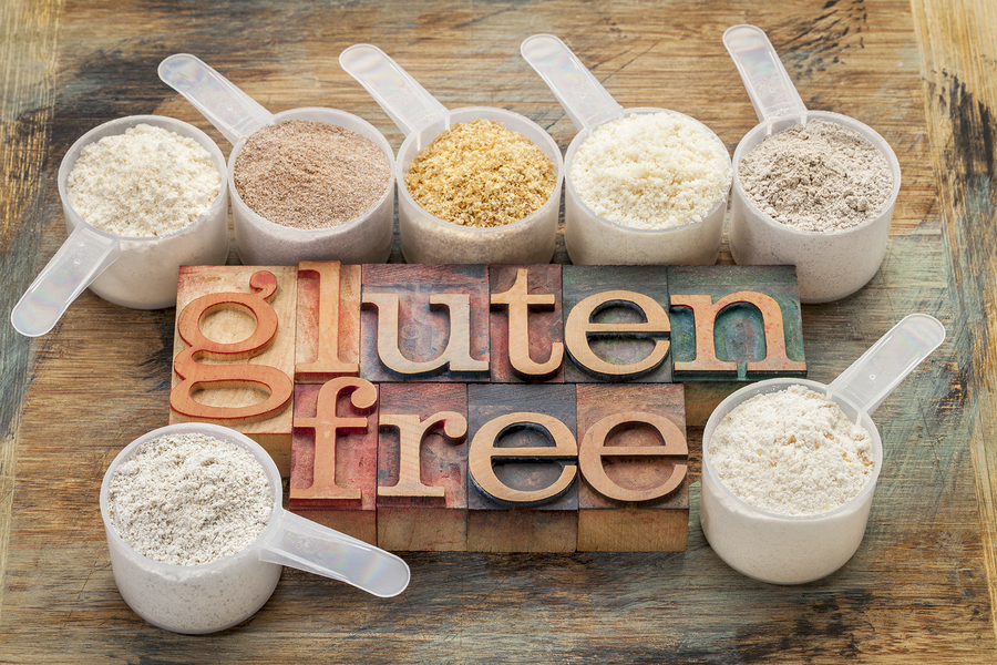 measuring scoops of gluten free flours (almond, coconut, teff, flaxseed meal, whole rice, brown rice, buckwheat) with a text in letterpress wood type