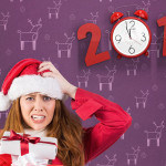 A woman in a santa outfit scratching her head while holding an armful of wrapped gifts. An old fashioned alarm clock is in the background forming the '0' part of a red numbered "2015"