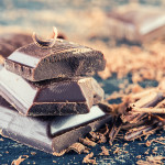 Chocolate. Black chocolate. A few cubes of black chocolate with mint leaves. Chocolate slabs spilled from grated chockolate powder.