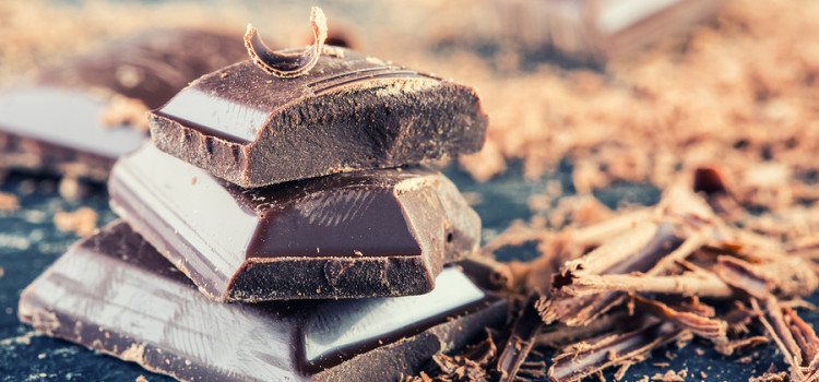 Chocolate. Black chocolate. A few cubes of black chocolate with mint leaves. Chocolate slabs spilled from grated chockolate powder.