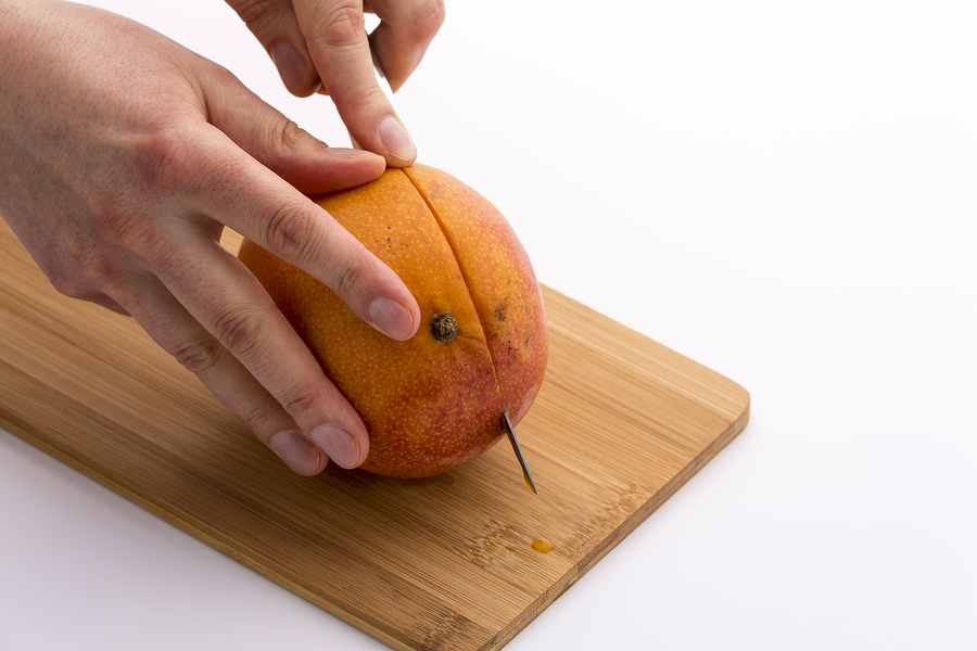 A Mango being cut just off of center