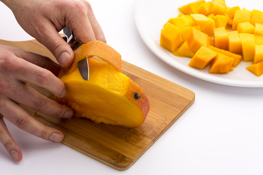 A mango being cut into slices and cubes