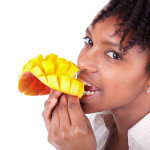A young African-American woman eating a sliced and cubed mango