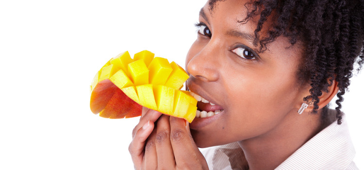 A young African-American woman eating a sliced and cubed mango