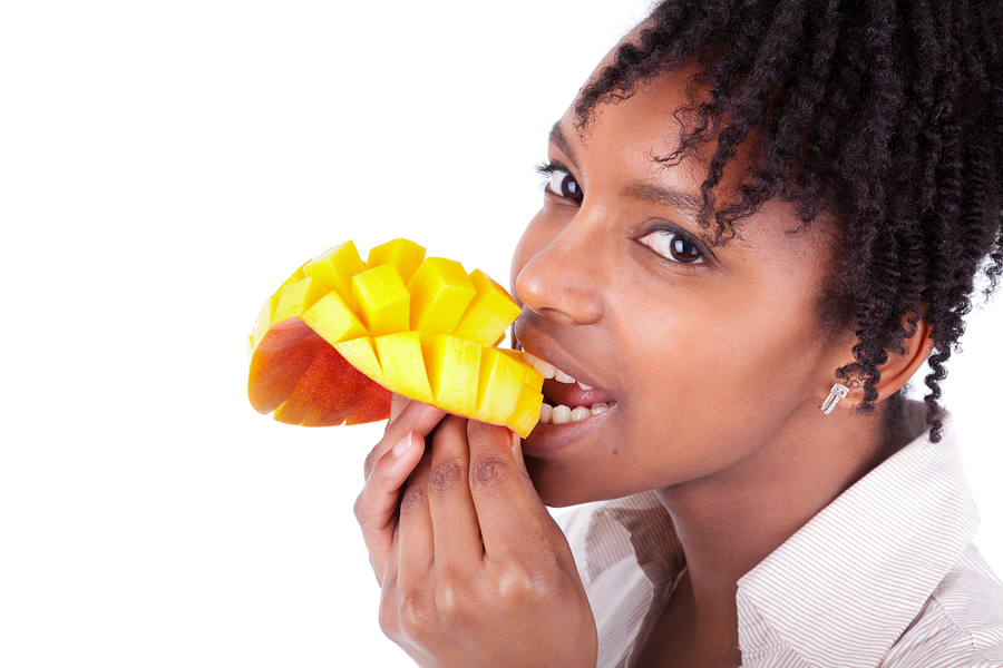A young African-American woman eating a sliced and cubed mango