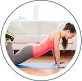 A woman doing a three quarter push up on the floor of her living room. The couch is in the background