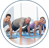 A group of people in an gym doing push ups together