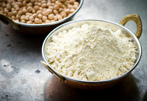 Chickpea Flour in a metal bowl with a bowl of chickpeas in another bowl behind it.