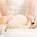 Pair of woman's hands kneading gluten free dough on table. Close-up