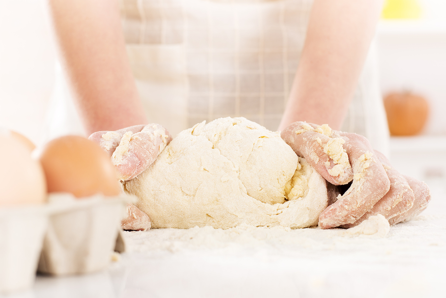 Pair of woman's hands kneading gluten free dough on table. Close-up