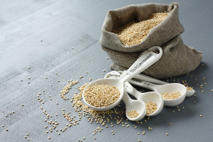 Quinoa Grain In Small Burlap Sack And Porcelain Measuring Spoons