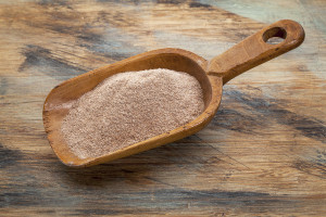 Swhole grain teff flour in a wooden spoon on a wooden table