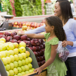 A woman and young girl shopping for fruit in a grocery store